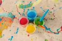 Cups of sidewalk chalk paint surrounded by paint splatter