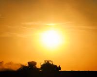 Silhouette of tractor in a field, bright sun