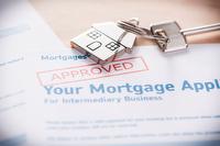 Photo of mortgage application paperwork and key with house shaped keychain.