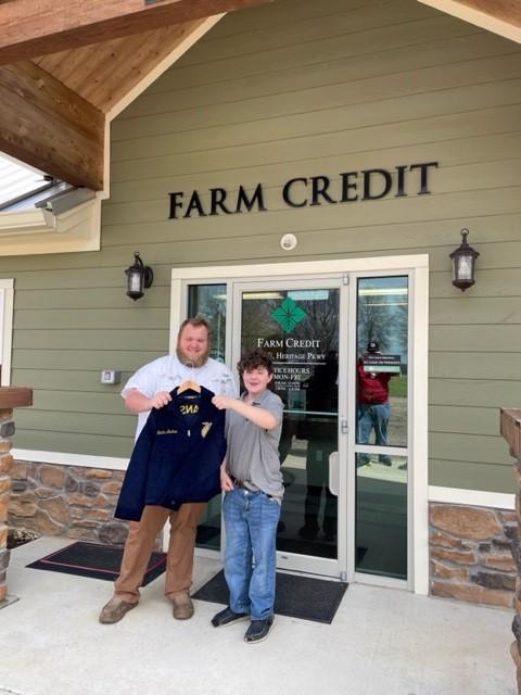 Man stands with young male student holding FFA jacket