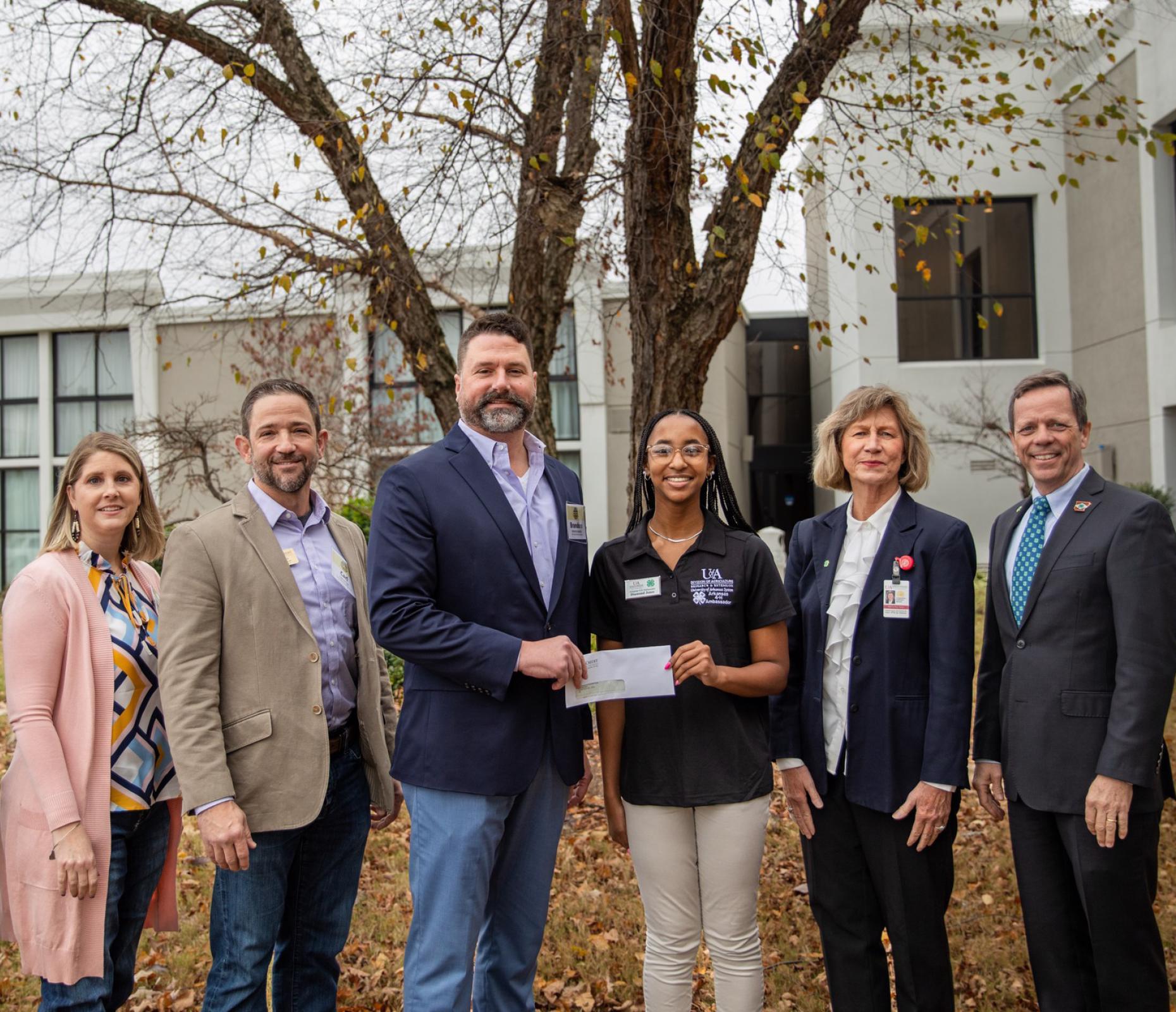 CEO Brandon Haberer presents a check for $6,990 to a student representative of Arkansas 4-H., Dr. Martha Sartor and John Thompson of the AR 4-H Foundation.