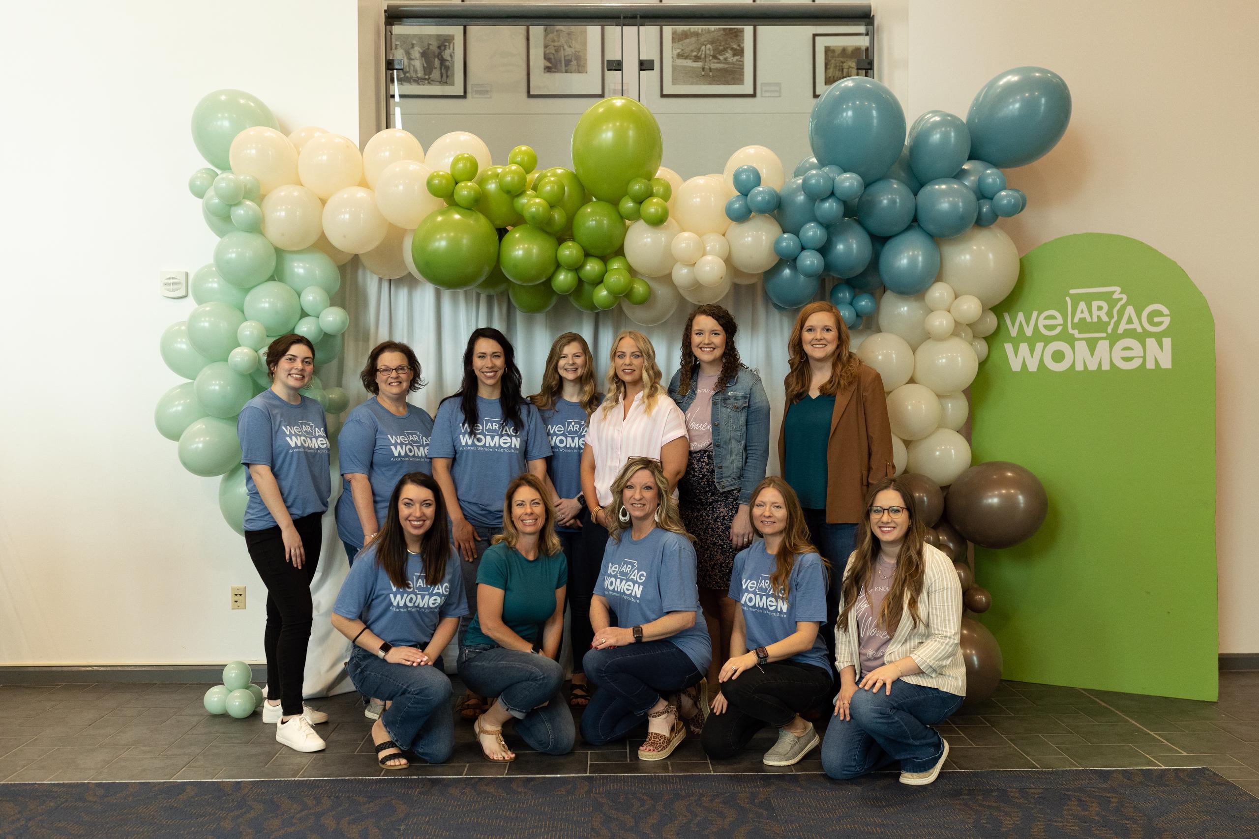 12 women stand in front of balloon arch at Arkansas Women in Ag Conference