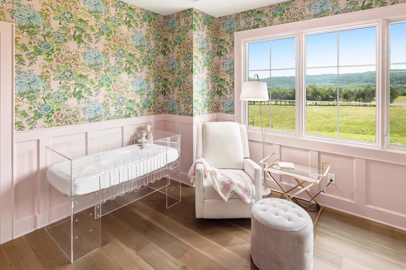 The nursery combines pink board-and-batten walls with a colorful floral wallpaper selected to grow with the family’s youngest daughter. 