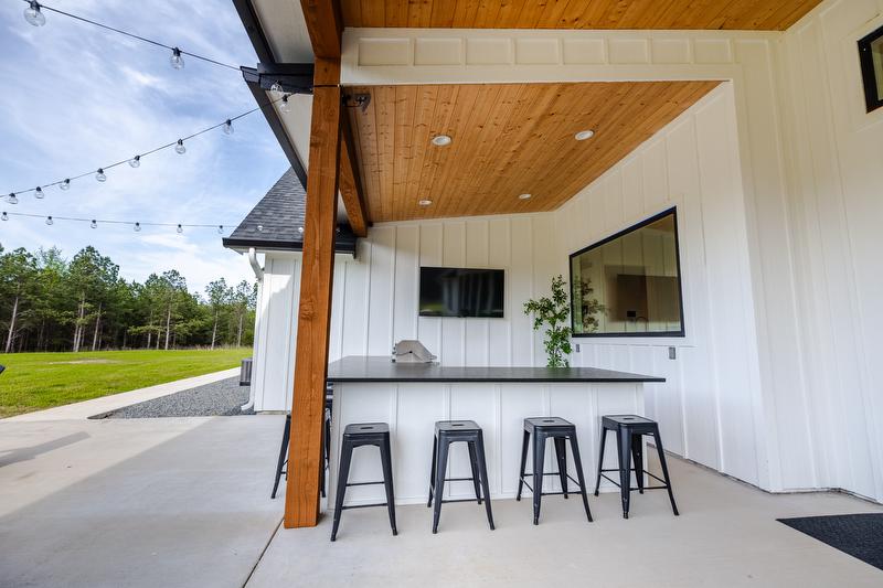 Outdoor kitchen space with black countertops and stools