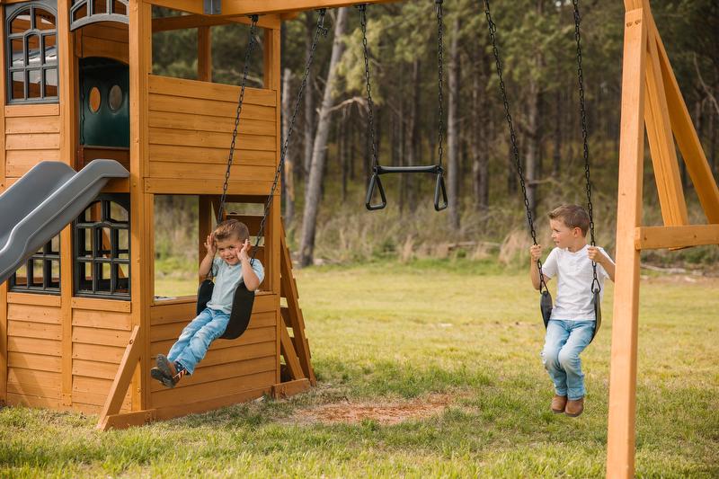 Two young boys play on swing set