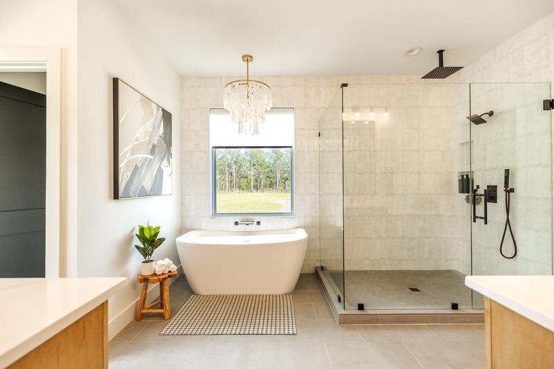 Bathroom with large window, freestanding tub, glass shower with dark fixtures