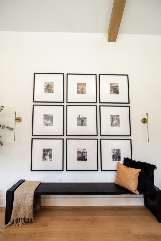 Large gallery wall with square frames, long wooden bench