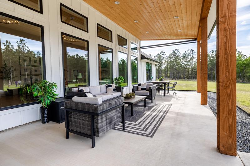 Outdoor seating area with dark patio furniture and large windows
