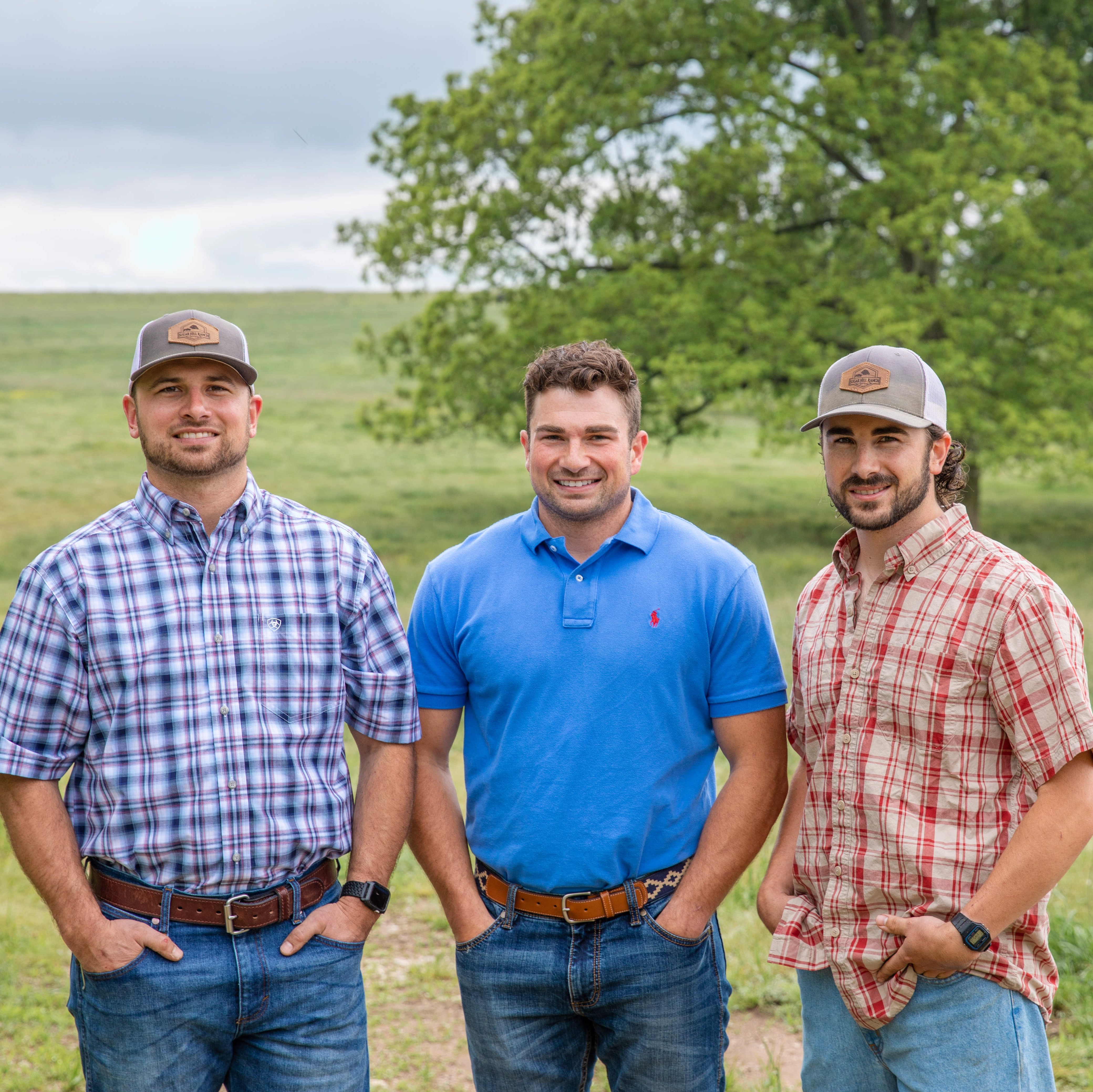 Three young men, standing in pasture