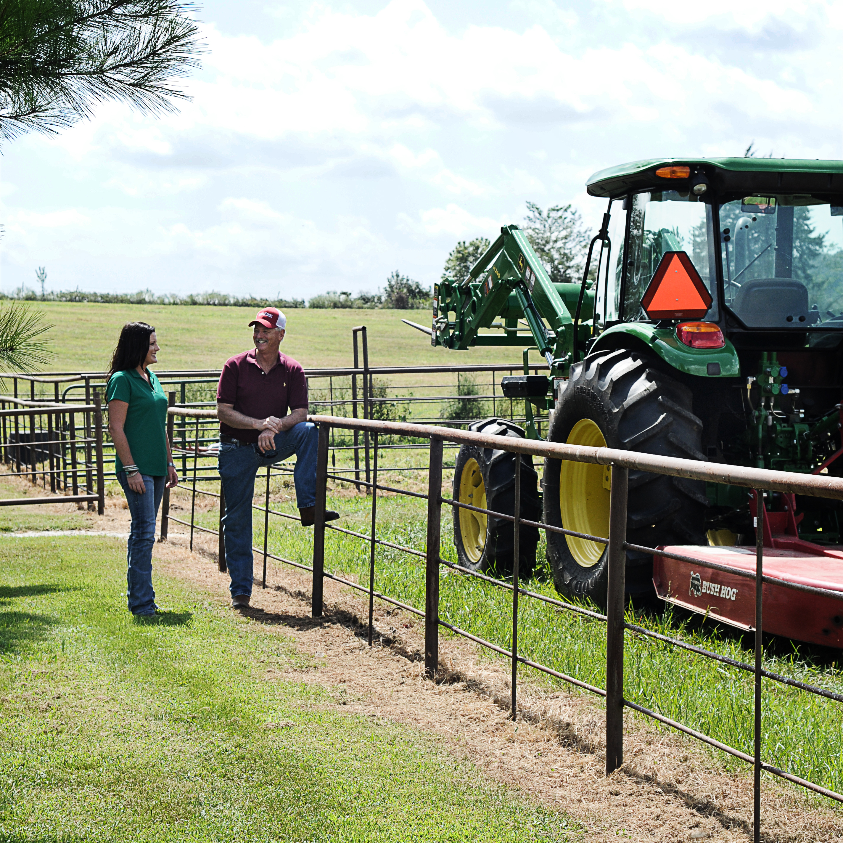 farmer talks to loan officer against fence