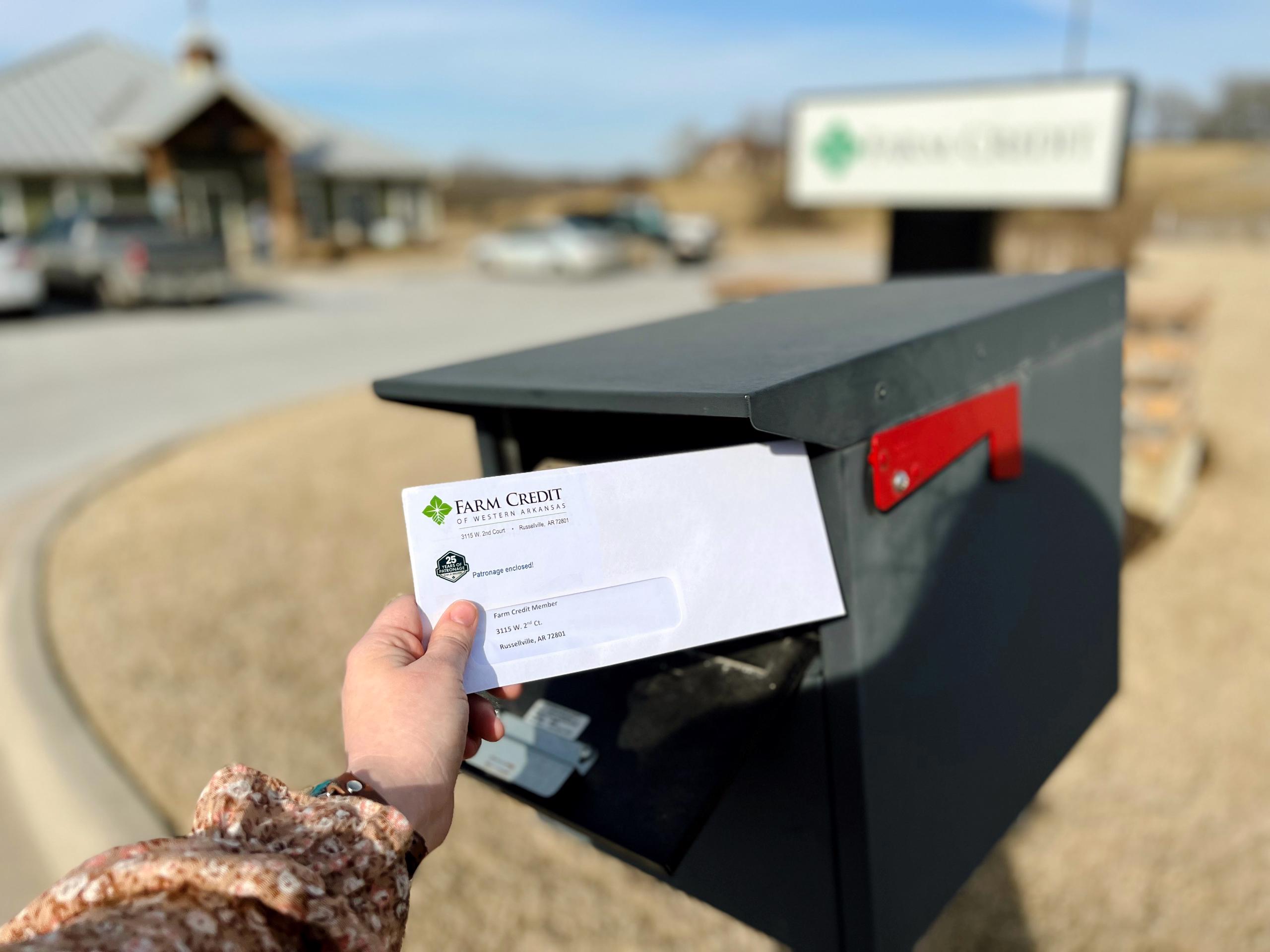 Hand putting patronage check in mailbox