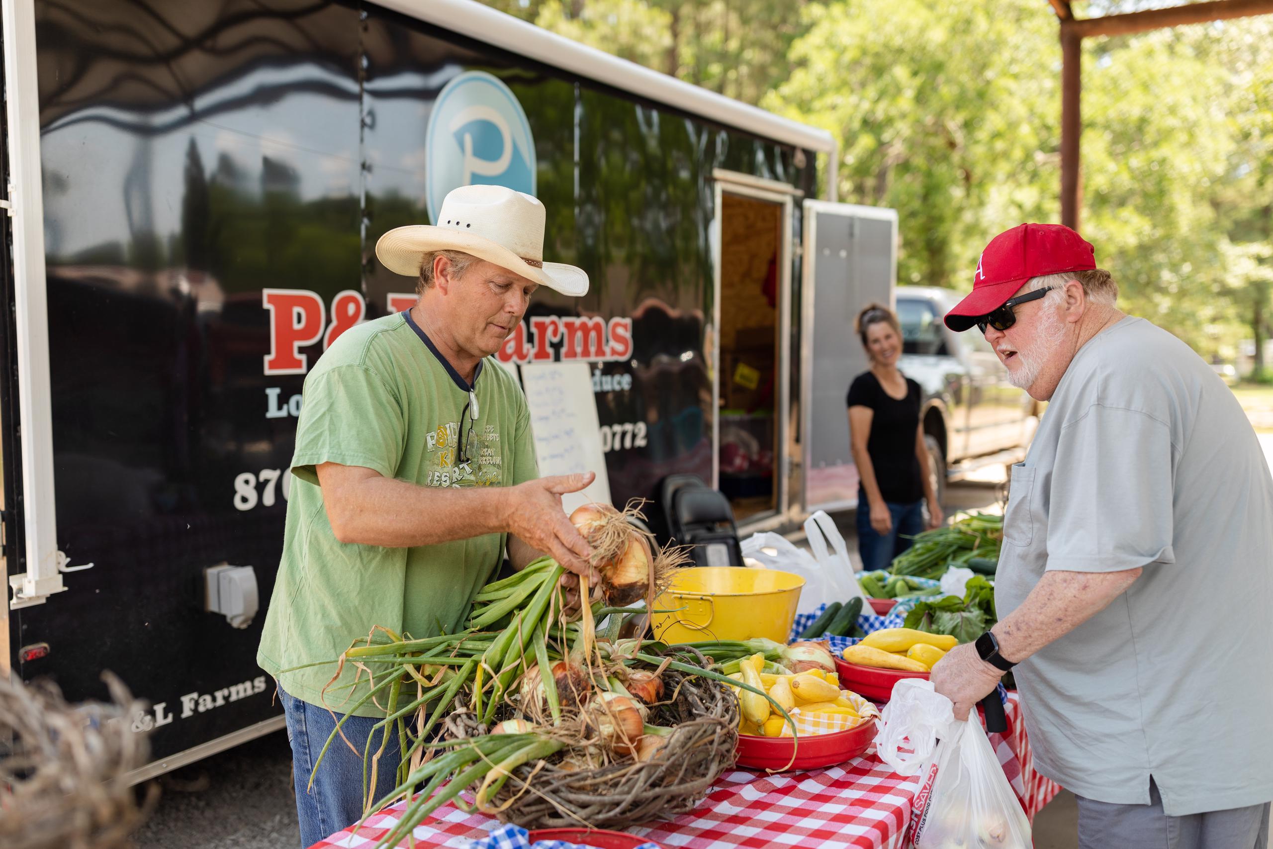 Man buys onions at Emerson Farmers Market