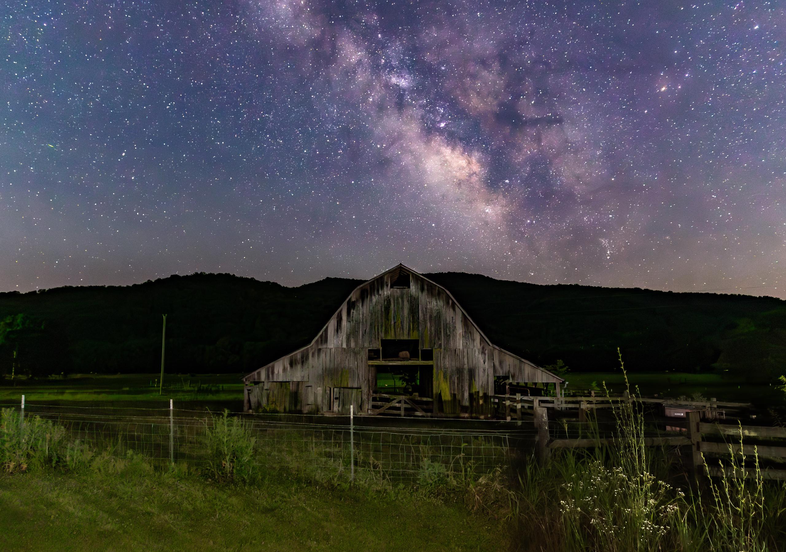 Milky way sky behind old barn.